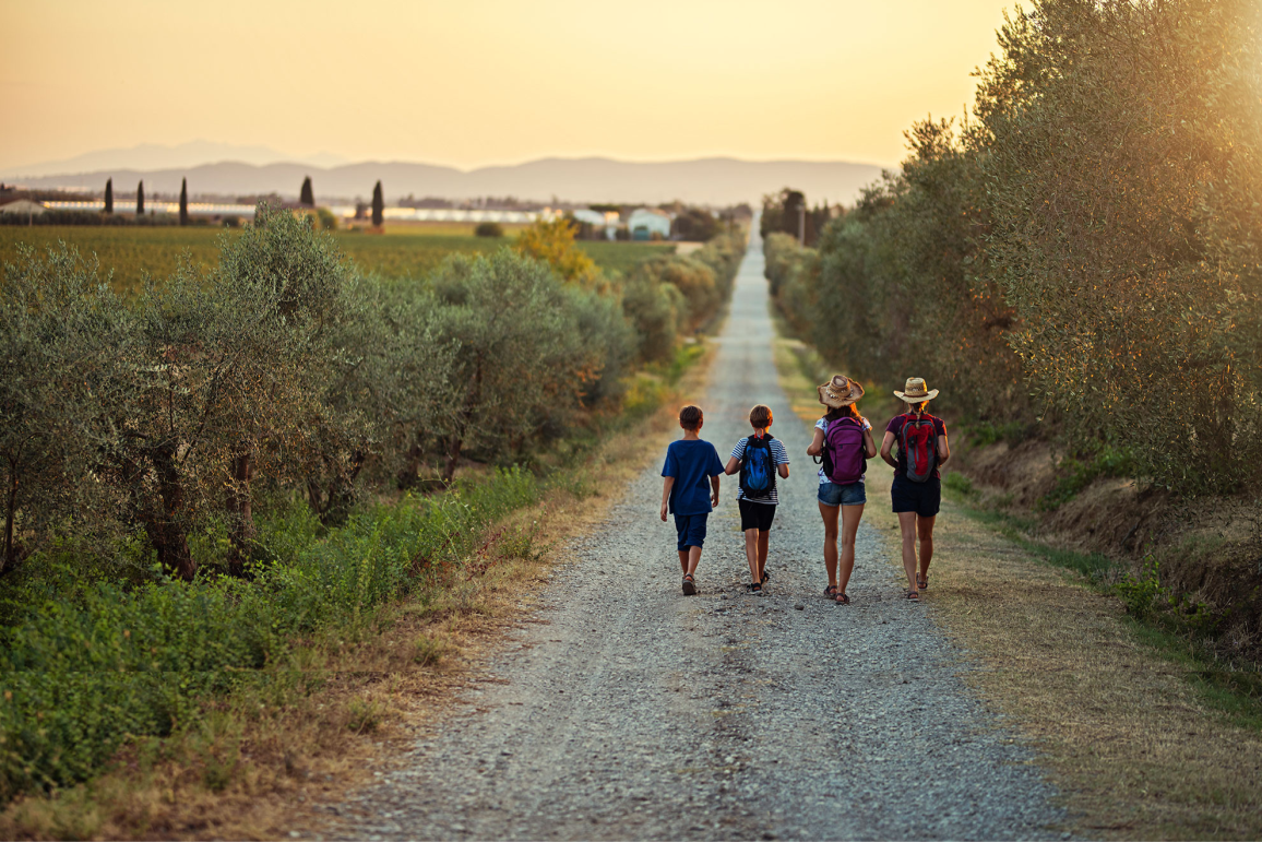 Family hiking on dirt road in Tuscany