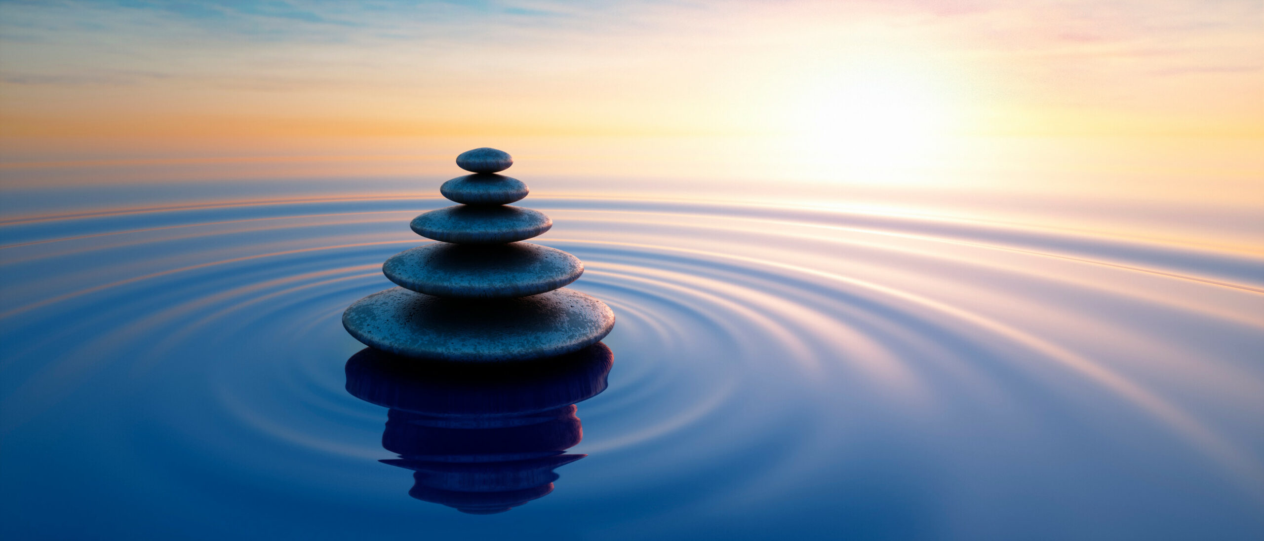 Stacked-Smooth-Stones-in-Water-Ripple-Sunrise-iStock-1564441923-scaled.jpg